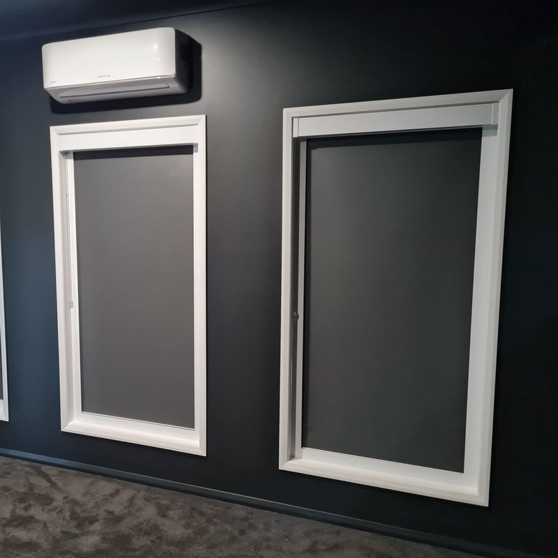 Dark roller blinds in white framed windows on a navy feature wall