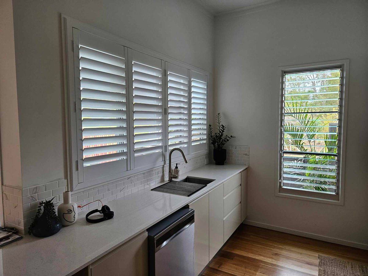 White plantation shutters over a kitchen sink and side window