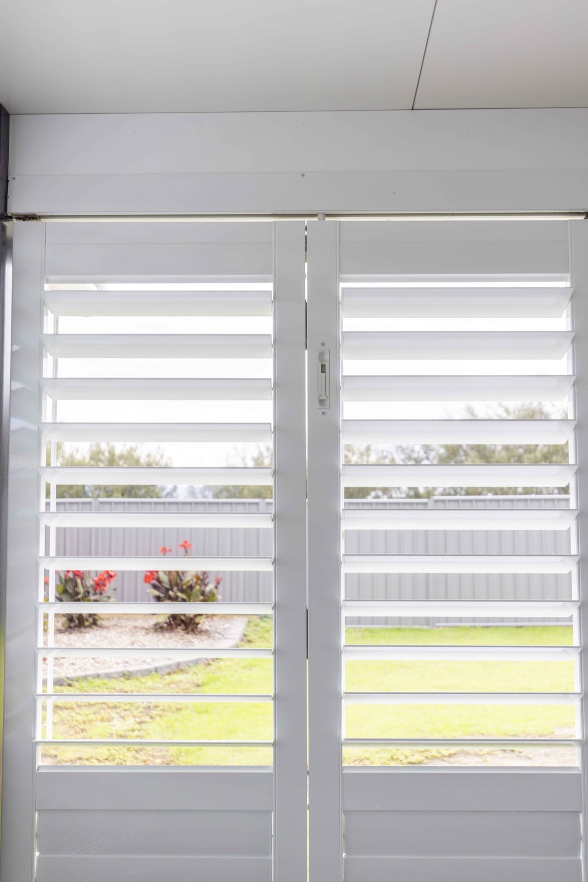 Pair of white aluminium shutter doors with the blades open to the garden